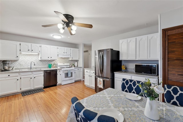 kitchen featuring appliances with stainless steel finishes, tasteful backsplash, sink, light hardwood / wood-style flooring, and white cabinetry