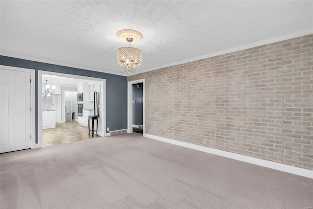 carpeted spare room featuring brick wall and an inviting chandelier