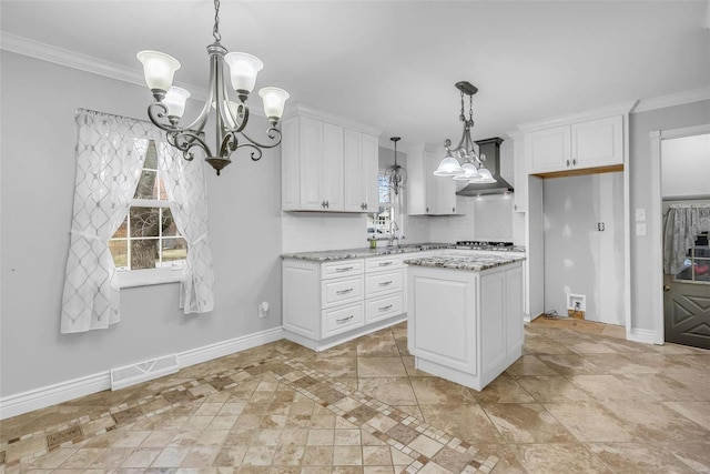 kitchen with white cabinetry, a center island, wall chimney exhaust hood, light stone counters, and pendant lighting