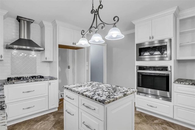 kitchen with white cabinets, hanging light fixtures, wall chimney range hood, and appliances with stainless steel finishes