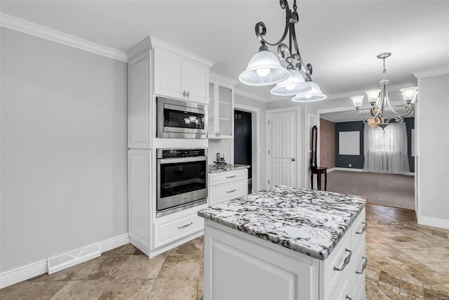 kitchen featuring appliances with stainless steel finishes, crown molding, white cabinets, a chandelier, and a kitchen island