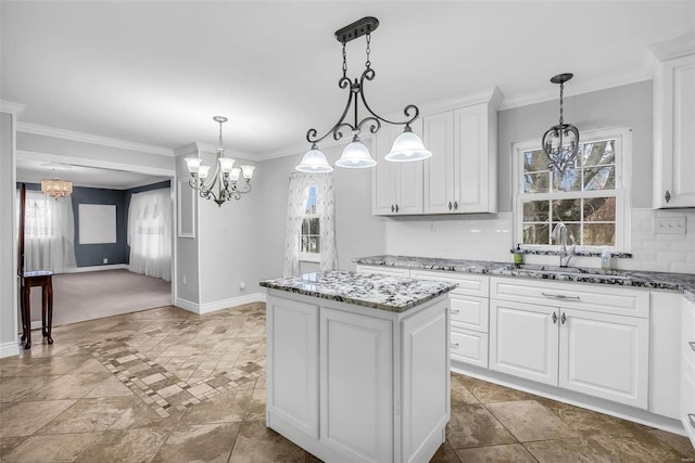 kitchen featuring backsplash, sink, pendant lighting, a center island, and white cabinetry