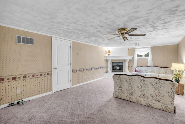 unfurnished living room with ceiling fan, a textured ceiling, and ornamental molding