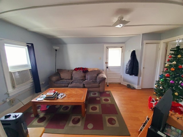 living room featuring plenty of natural light, cooling unit, vaulted ceiling, and light wood-type flooring