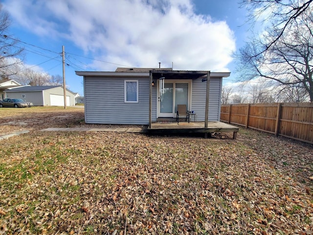 rear view of house with fence, a deck, and a detached garage