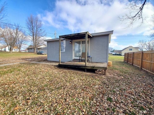 rear view of property featuring fence, a lawn, and a wooden deck