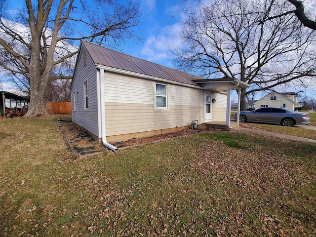 view of side of home with fence, metal roof, and a yard