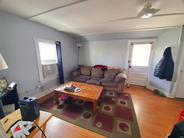 living area featuring lofted ceiling, light wood-style floors, cooling unit, and a healthy amount of sunlight