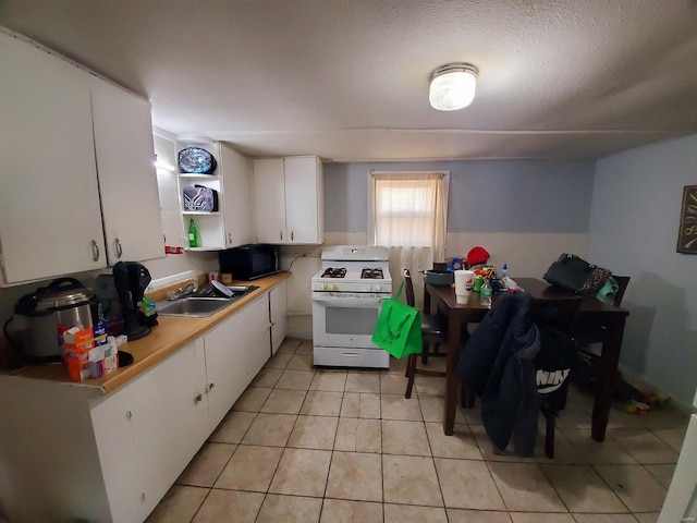 kitchen with black microwave, white gas range, a sink, and white cabinetry