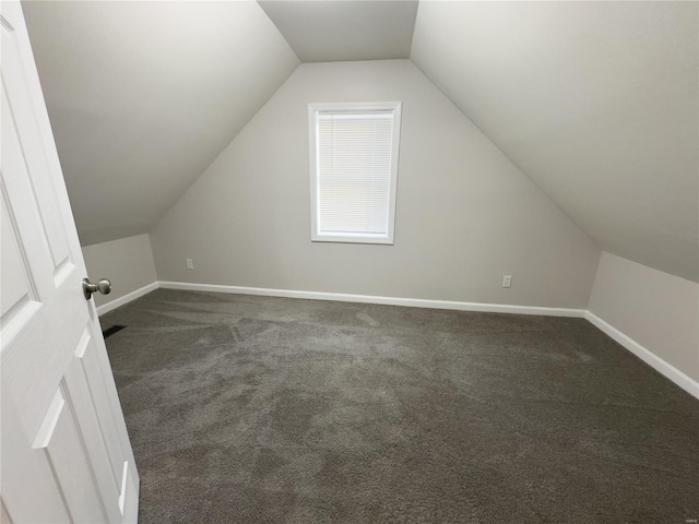 additional living space featuring dark carpet and lofted ceiling