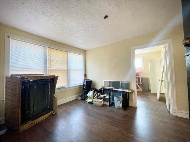 misc room with plenty of natural light, a textured ceiling, baseboards, and wood finished floors