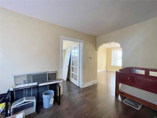 bedroom featuring baseboards, visible vents, arched walkways, and wood finished floors