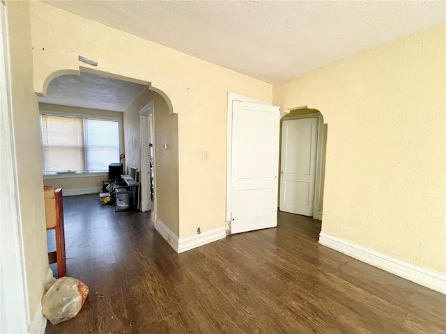 spare room featuring a textured ceiling and dark hardwood / wood-style flooring