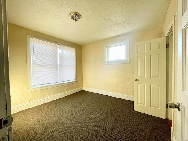 empty room with a textured ceiling and dark carpet