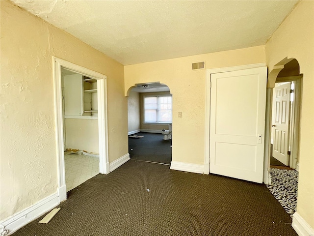 corridor featuring dark colored carpet