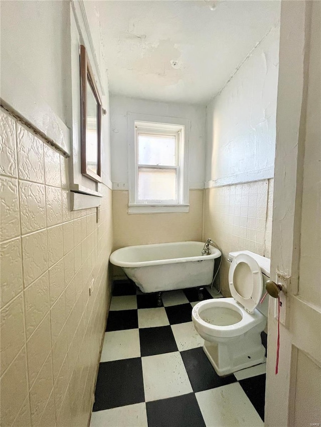 bathroom featuring a bath, tile walls, and toilet