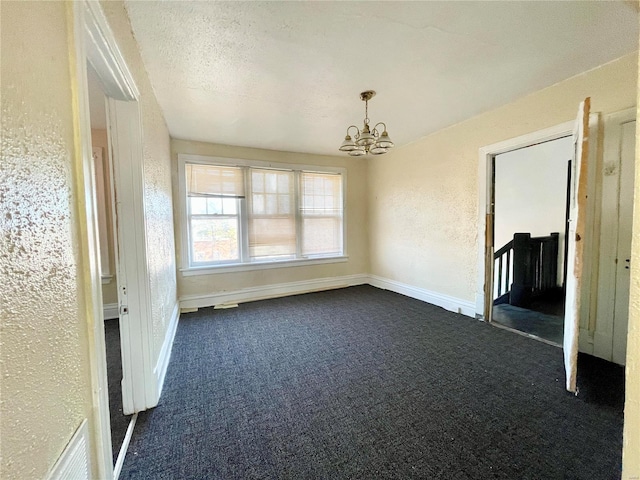 unfurnished dining area featuring dark colored carpet, a textured ceiling, and a chandelier