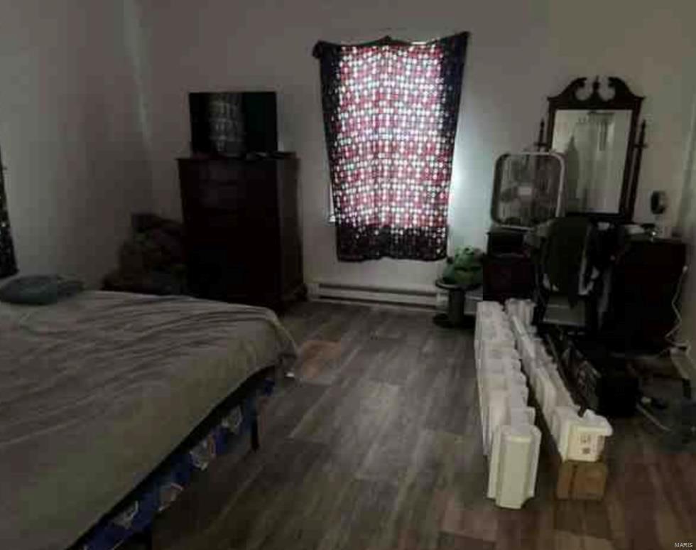 bedroom with dark wood-type flooring and a baseboard heating unit