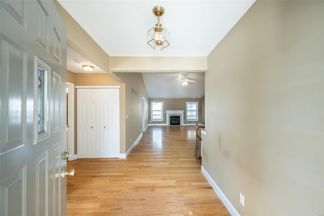 corridor with an inviting chandelier, lofted ceiling, and light hardwood / wood-style flooring