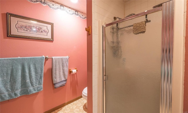 bathroom featuring toilet and a shower with shower door