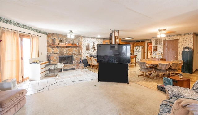 carpeted living room featuring ceiling fan and a stone fireplace