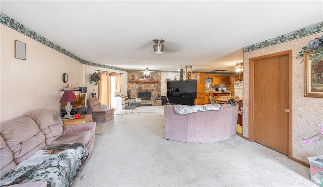 carpeted living room featuring ceiling fan and a stone fireplace