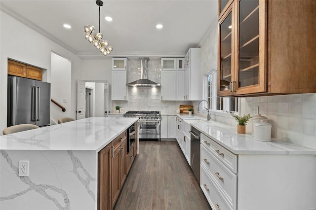 kitchen featuring a center island, wall chimney range hood, tasteful backsplash, premium appliances, and white cabinetry