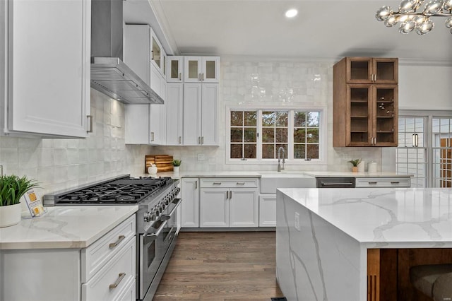 kitchen with light stone countertops, dark hardwood / wood-style flooring, wall chimney range hood, high end stainless steel range, and white cabinets