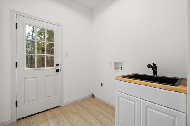 washroom with hookup for an electric dryer, hookup for a washing machine, cabinets, sink, and light hardwood / wood-style floors