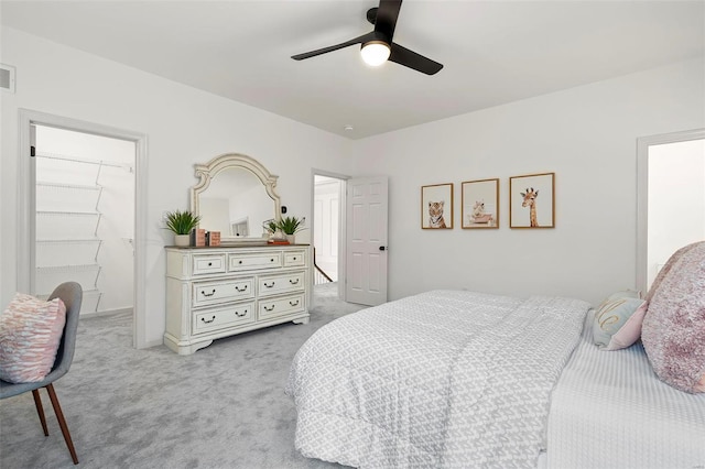 bedroom with light carpet, a spacious closet, a closet, and ceiling fan