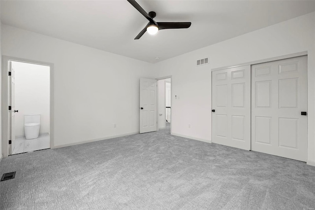 unfurnished bedroom featuring carpet flooring, ensuite bath, ceiling fan, and a closet