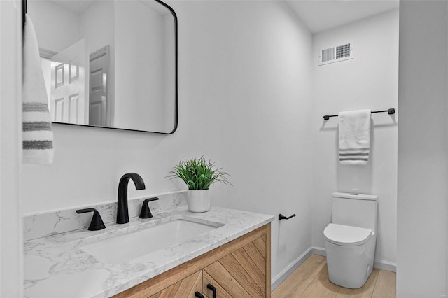 bathroom with vanity, hardwood / wood-style flooring, and toilet