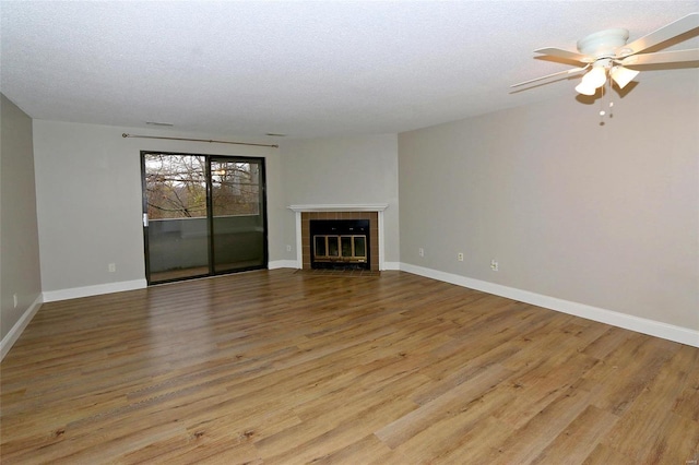 unfurnished living room with a textured ceiling, ceiling fan, light hardwood / wood-style floors, and a fireplace