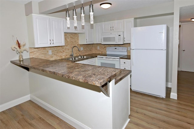 kitchen featuring kitchen peninsula, white appliances, sink, decorative light fixtures, and white cabinets