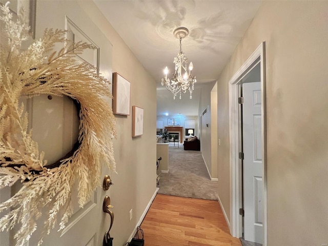 hall featuring light wood-type flooring and a chandelier