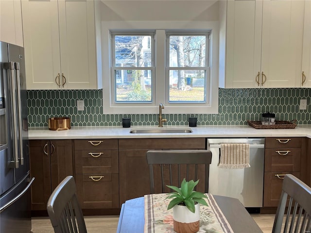 kitchen with backsplash, sink, white cabinetry, and stainless steel appliances