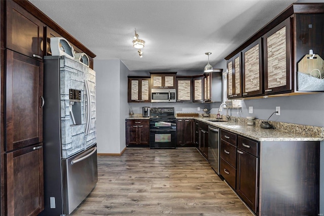 kitchen featuring pendant lighting, sink, stainless steel appliances, light hardwood / wood-style floors, and light stone countertops