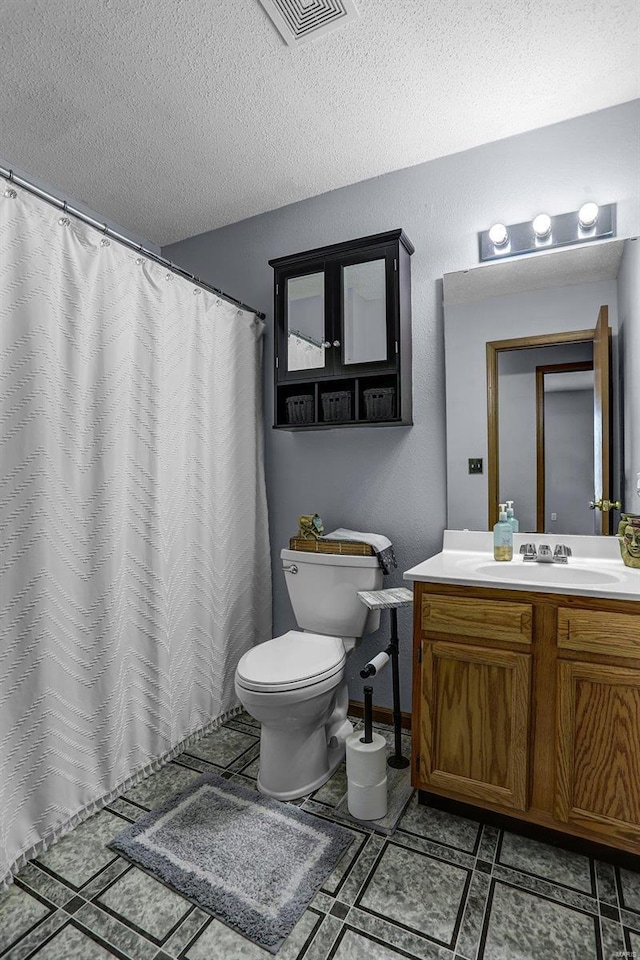 bathroom featuring vanity, a textured ceiling, and toilet