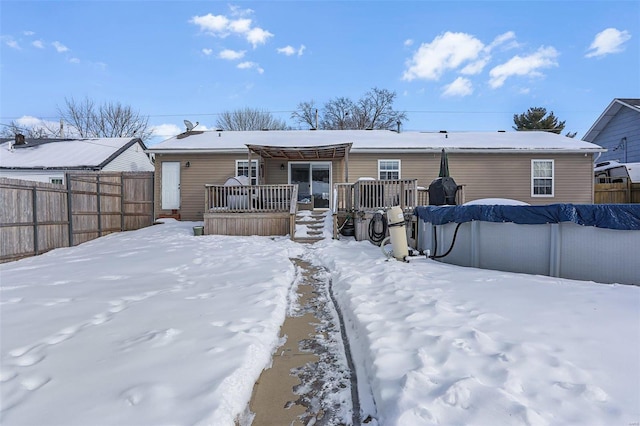 snow covered back of property featuring a pool side deck