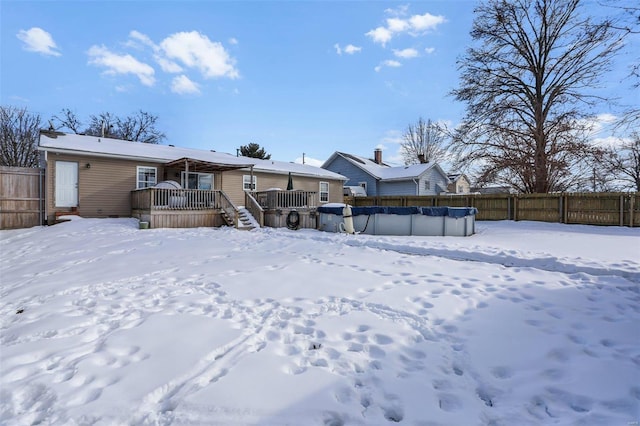 snow covered back of property with a covered pool