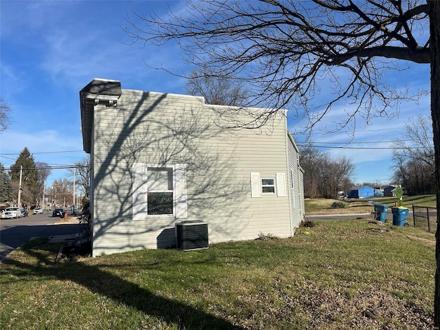 view of side of property featuring a lawn and cooling unit