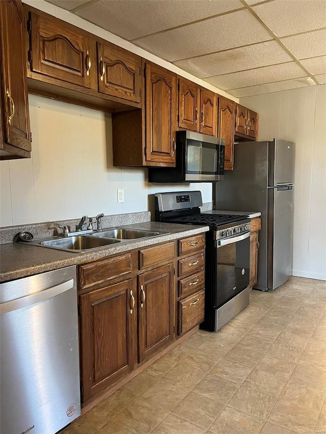 kitchen featuring wood walls, sink, and appliances with stainless steel finishes