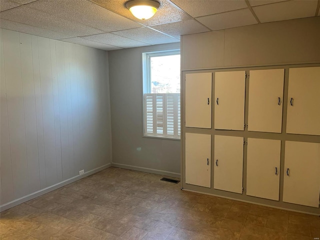 empty room with a drop ceiling and wooden walls