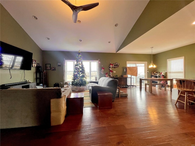 living room featuring vaulted ceiling, ceiling fan with notable chandelier, and hardwood / wood-style flooring