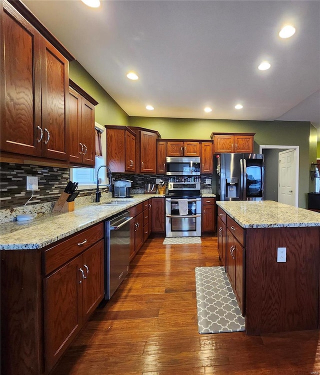 kitchen with light stone countertops, stainless steel appliances, tasteful backsplash, and sink