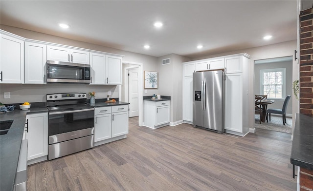 kitchen with white cabinetry, hardwood / wood-style flooring, and appliances with stainless steel finishes