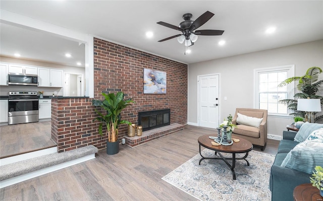 living room with a fireplace, light hardwood / wood-style floors, and ceiling fan