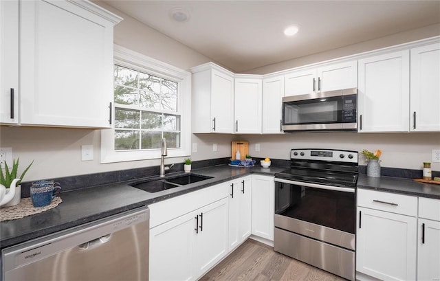 kitchen with sink, white cabinets, stainless steel appliances, and light wood-type flooring