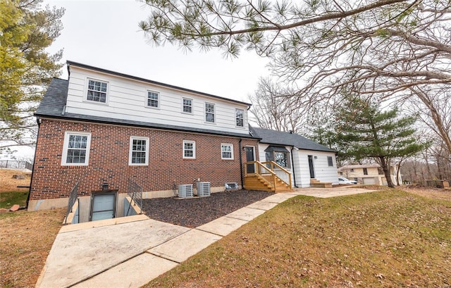 back of property featuring a lawn and central air condition unit