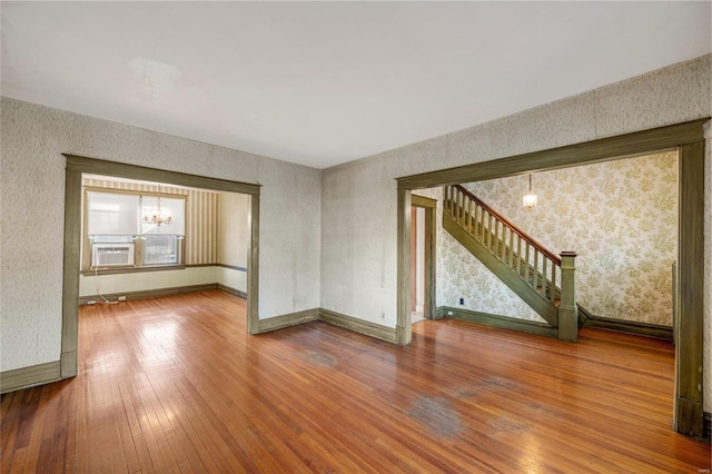 empty room featuring an inviting chandelier and hardwood / wood-style floors